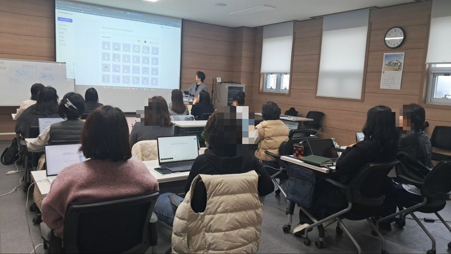 컴퓨터실에서 강사가 화면 앞에서 참가자들에게 교육하는 장면