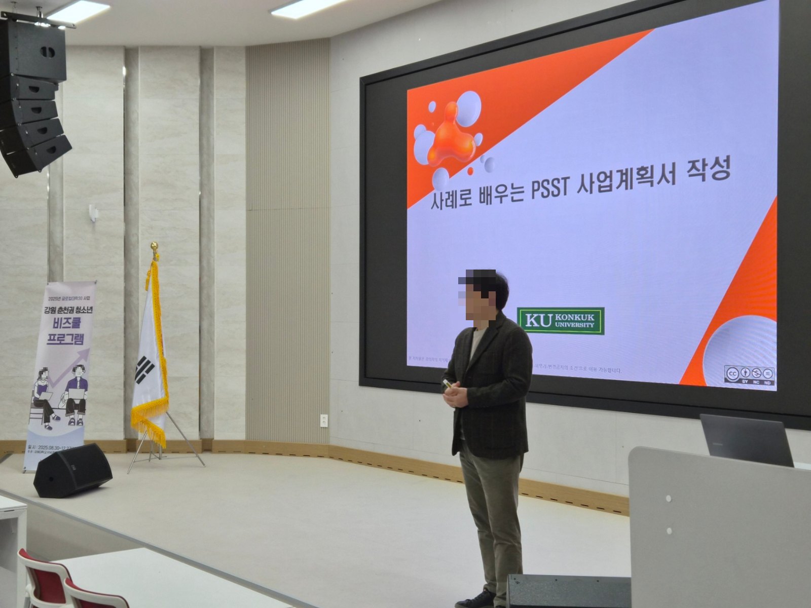 대형 화면 앞에서 강사가 PSST 사업계획서 작성법을 설명하는 장면