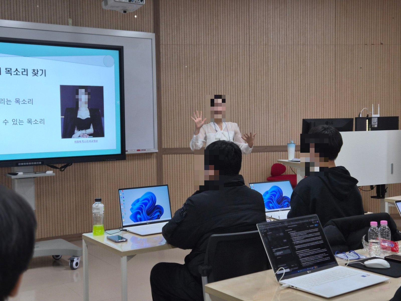 강의실에서 발표자가 프로젝터 화면 앞에서 강연하는 장면