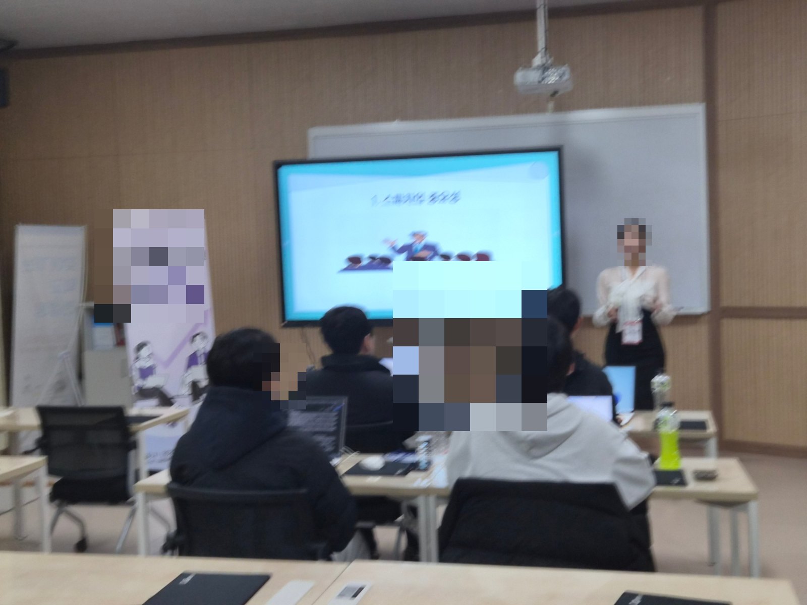 강의실에서 강연자가 화면 앞에서 교육 내용을 설명하는 장면