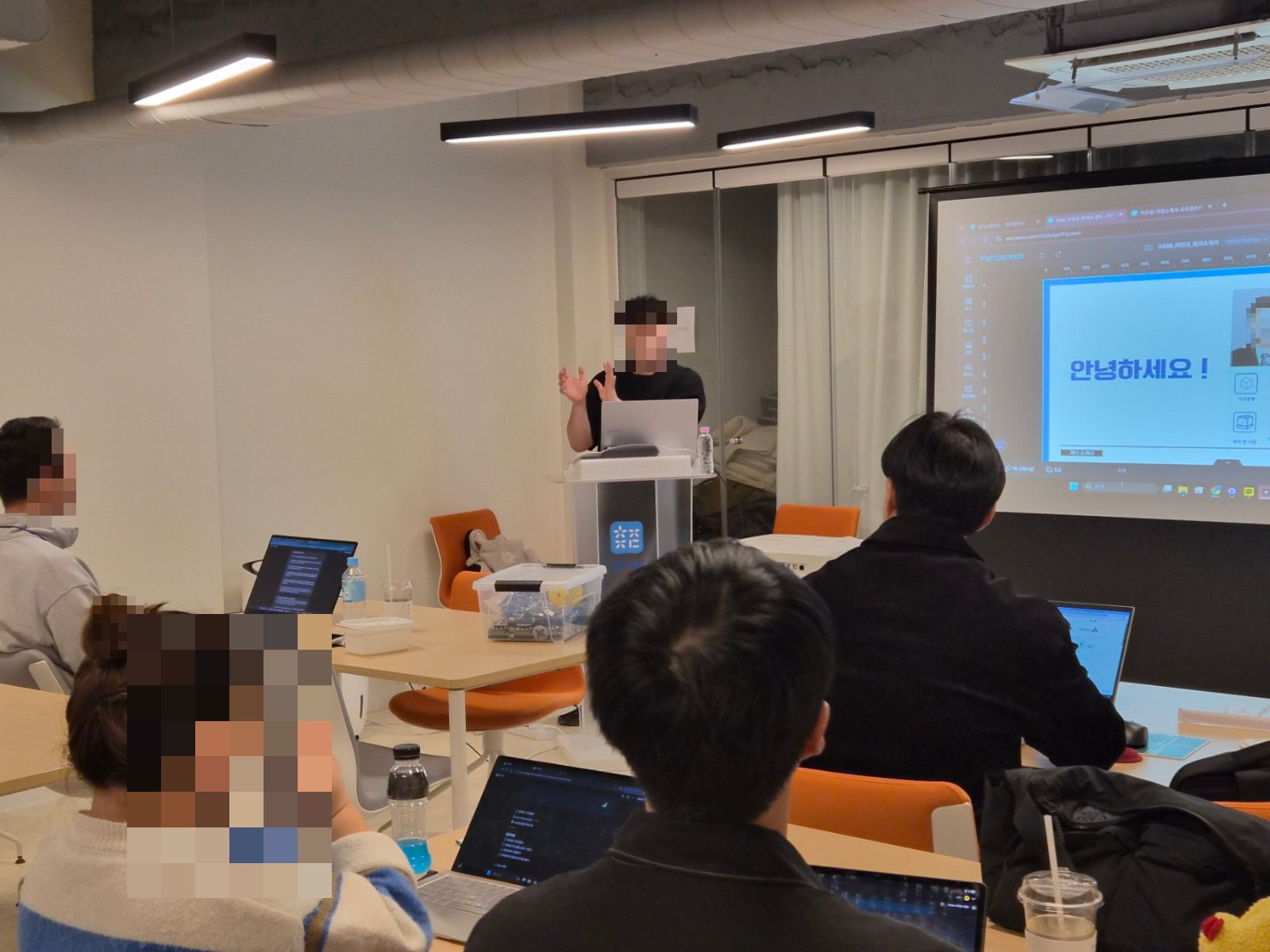 강의실에서 발표자가 화면 앞에서 참가자들에게 교육하는 장면
