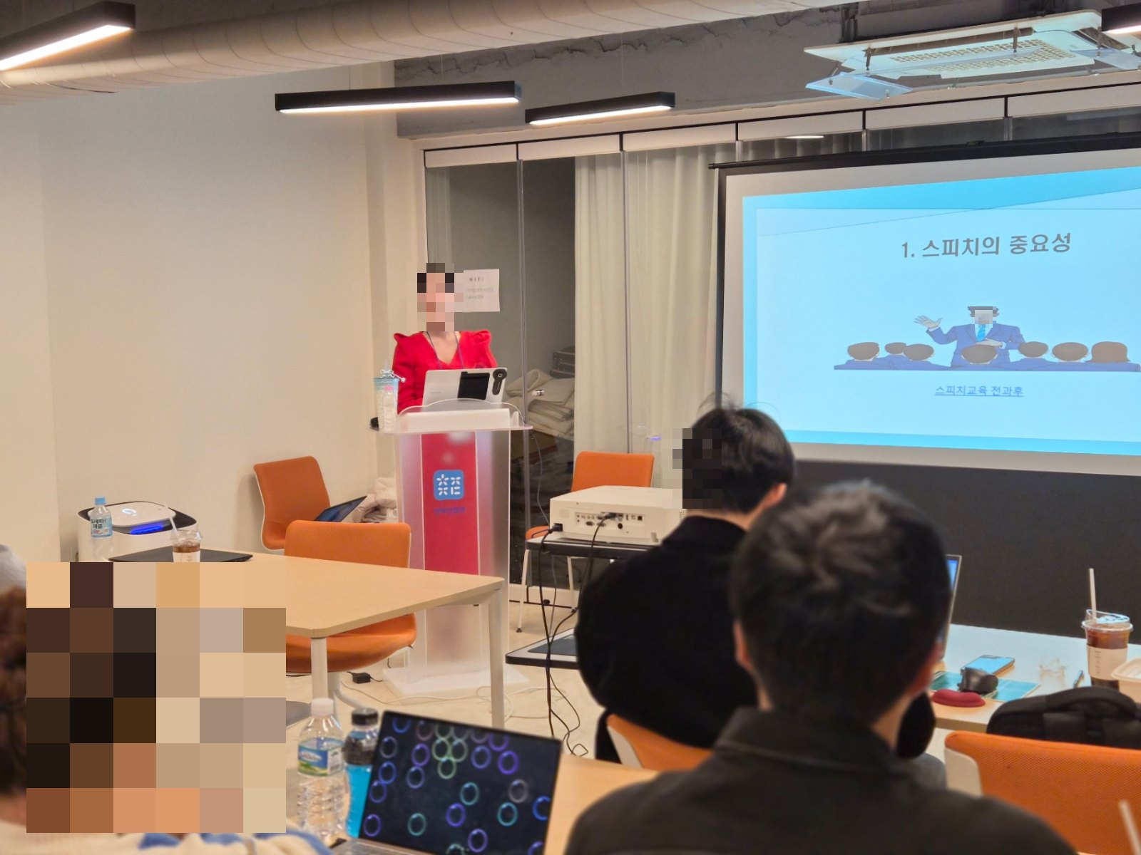 강의실에서 강연자가 스피치 교육 화면 앞에서 발표하는 장면